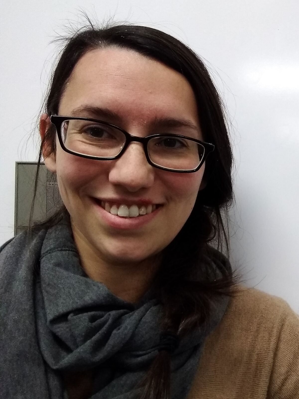 Rachel Goldsmith, smiling, in glasses and a gray scarf.